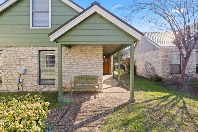 rear view of property with stone siding and a yard