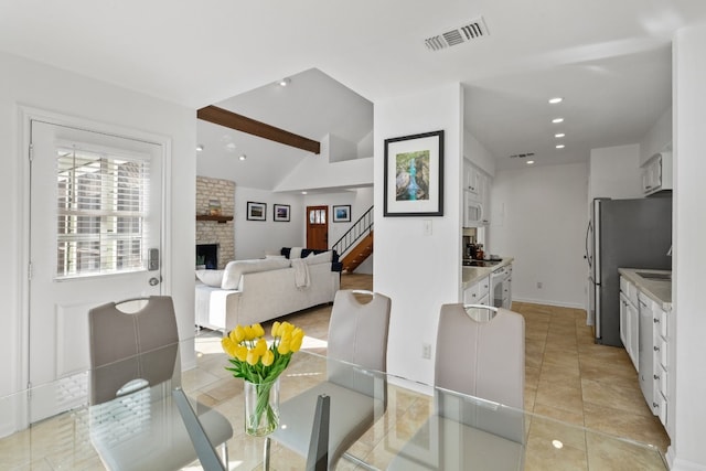 dining area featuring visible vents, stairway, vaulted ceiling with beams, a fireplace, and recessed lighting