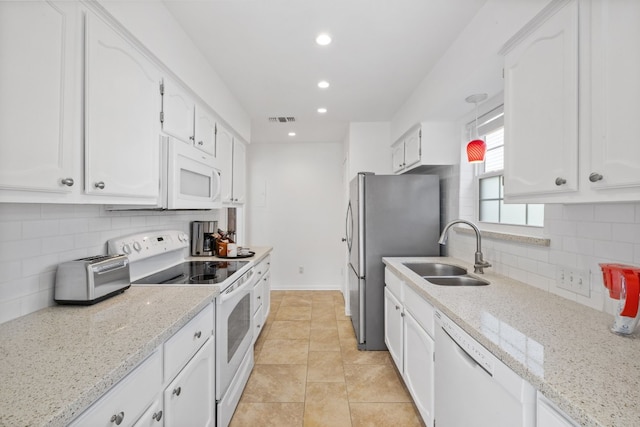 kitchen featuring white appliances, visible vents, light stone countertops, white cabinetry, and a sink