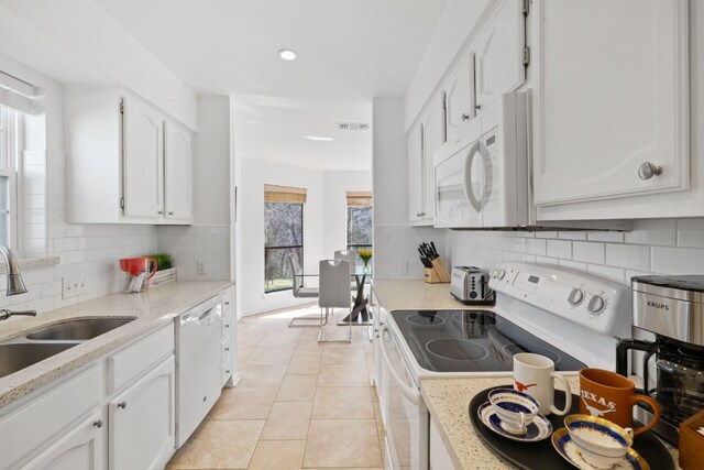 kitchen featuring white appliances, white cabinetry, a sink, and light tile patterned floors