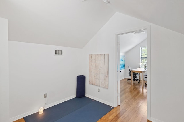 additional living space with lofted ceiling, visible vents, baseboards, and wood finished floors