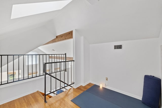 bonus room with baseboards, vaulted ceiling with skylight, visible vents, and wood finished floors