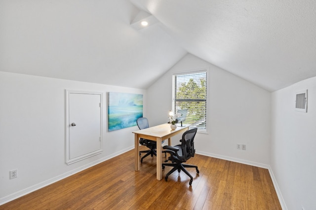 office space featuring visible vents, baseboards, vaulted ceiling, and wood finished floors