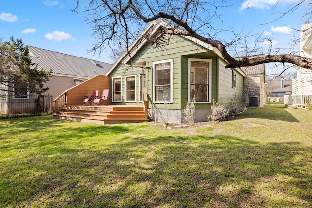 back of property featuring entry steps, central AC, a lawn, and fence