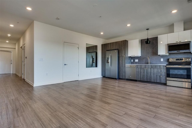 kitchen with stainless steel appliances, white cabinets, hanging light fixtures, light countertops, and modern cabinets