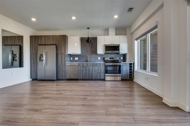 kitchen with stainless steel appliances, white cabinets, light countertops, modern cabinets, and pendant lighting