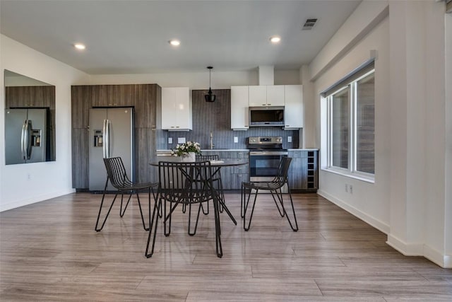 kitchen with light countertops, hanging light fixtures, appliances with stainless steel finishes, white cabinets, and modern cabinets