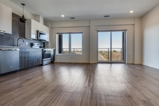 4361 S Congress Ave Unit 504, Austin, TX 78745 - kitchen with appliances with stainless steel finishes, backsplash, modern cabinets, dark wood-type flooring, and white cabinetry