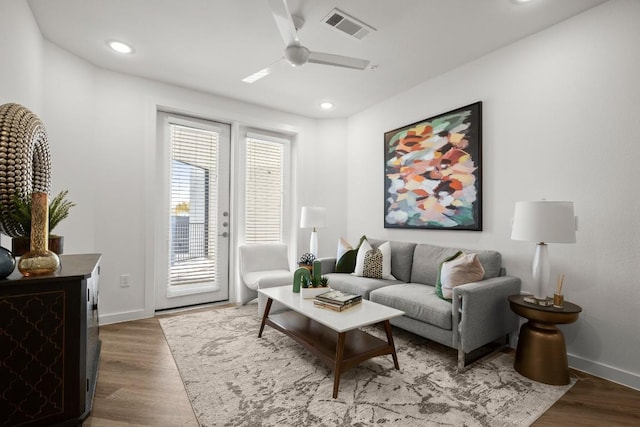 living room with baseboards, wood finished floors, visible vents, and a ceiling fan