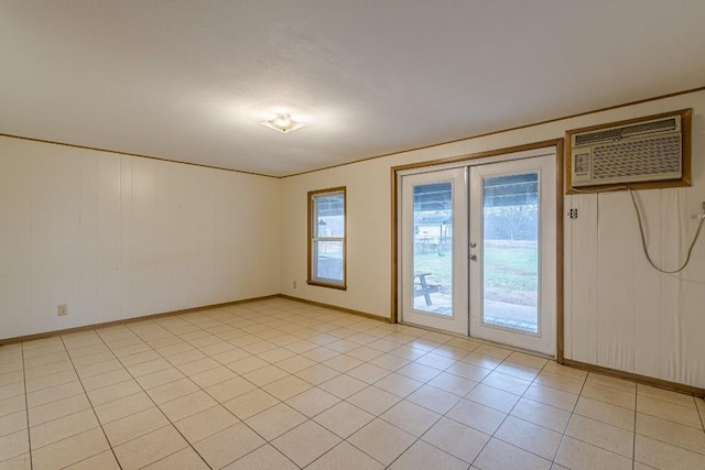 spare room with light tile patterned floors, an AC wall unit, french doors, and baseboards