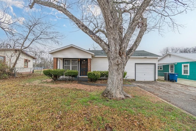 ranch-style house with a sunroom, aphalt driveway, an attached garage, fence, and a front lawn