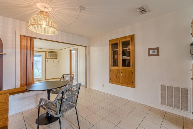 dining room featuring an AC wall unit, light tile patterned flooring, visible vents, and baseboards