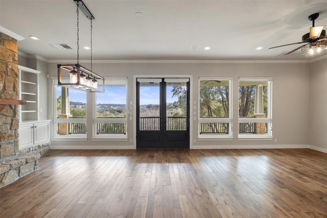 unfurnished dining area with built in shelves, a ceiling fan, baseboards, dark wood-style floors, and crown molding