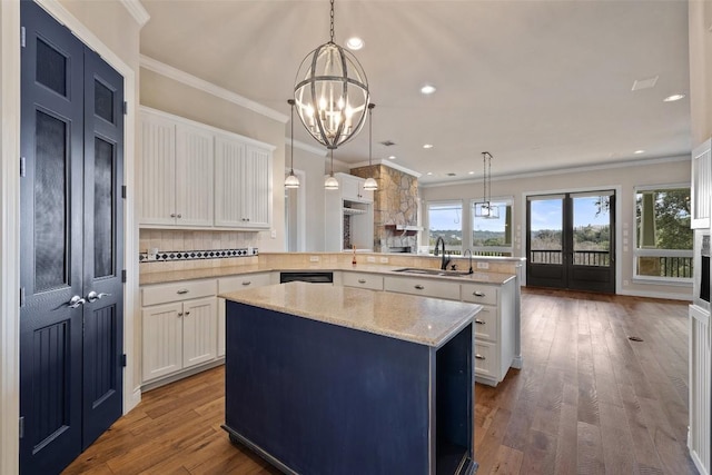 kitchen with a center island, hanging light fixtures, white cabinets, a sink, and a peninsula