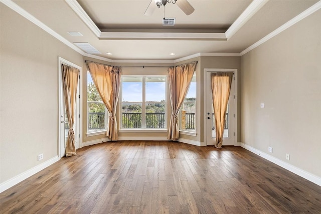 spare room with baseboards, visible vents, a raised ceiling, and wood finished floors