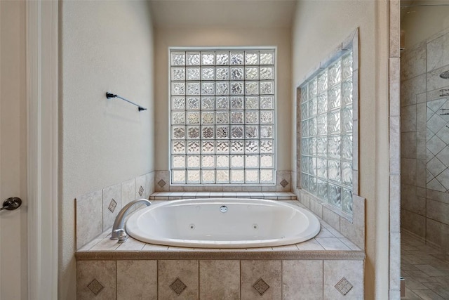 bathroom with a whirlpool tub, a healthy amount of sunlight, and tiled shower