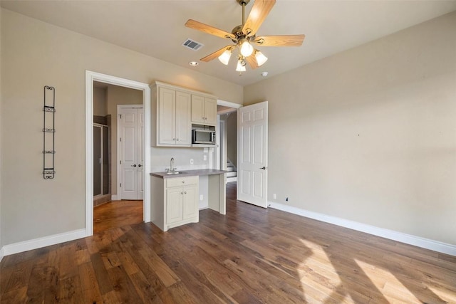 kitchen featuring dark wood finished floors, visible vents, white cabinetry, a sink, and baseboards