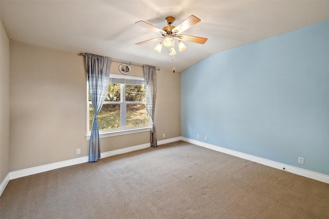 carpeted spare room featuring ceiling fan, vaulted ceiling, and baseboards