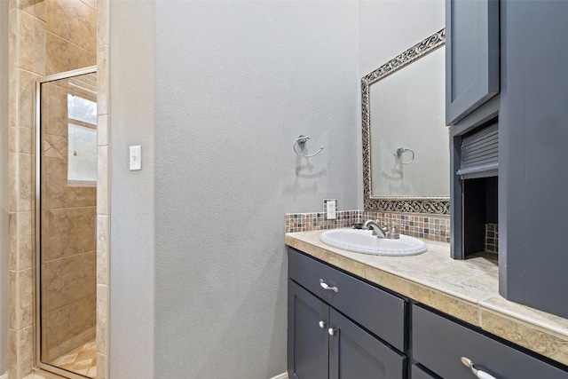 bathroom with tasteful backsplash, a stall shower, a textured wall, and vanity