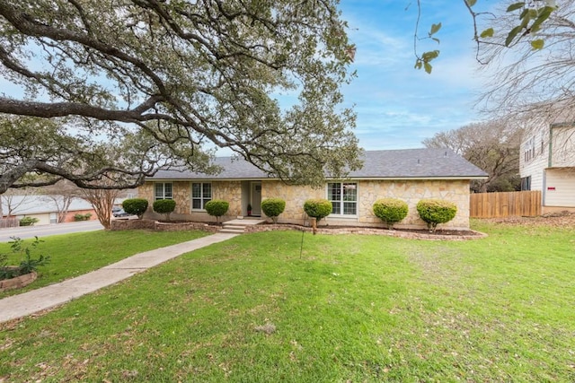 ranch-style house featuring stone siding, a front lawn, and fence