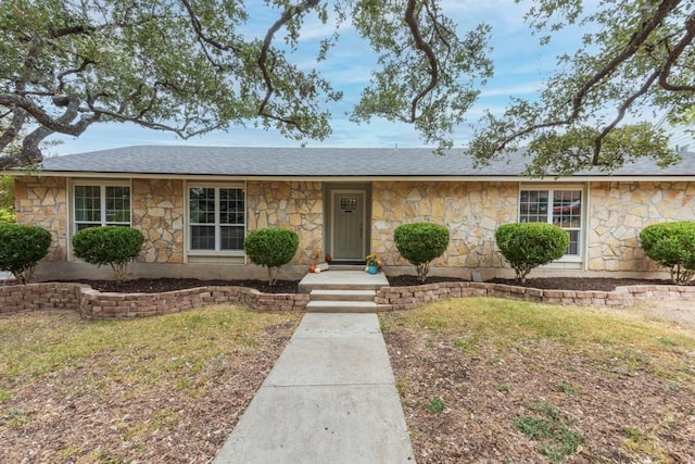 ranch-style house featuring a shingled roof and a front yard