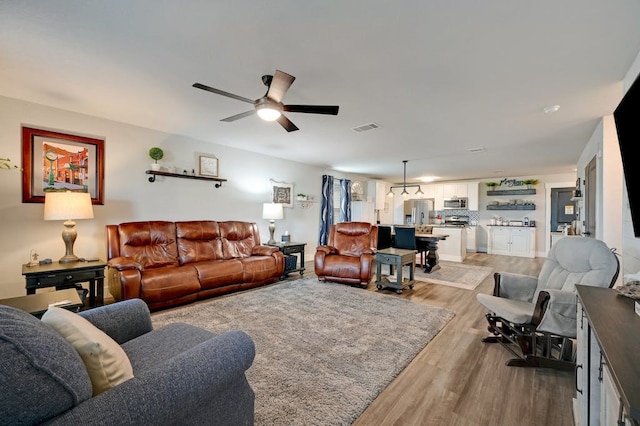 living room featuring visible vents, ceiling fan, and light wood finished floors