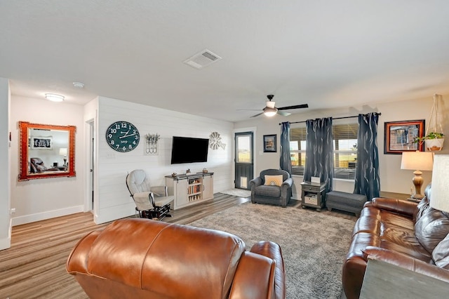 living room with light wood finished floors, ceiling fan, visible vents, and baseboards