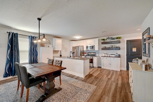 dining room featuring light wood-style floors, visible vents, and a textured ceiling