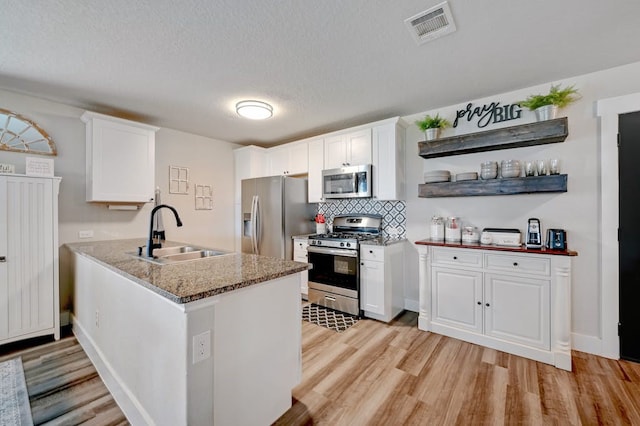 kitchen with light stone counters, a sink, visible vents, white cabinetry, and appliances with stainless steel finishes