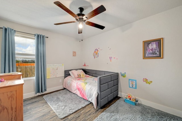 bedroom with ceiling fan, wood finished floors, and baseboards