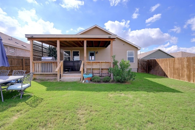 rear view of house with a fenced backyard, a deck, and a yard