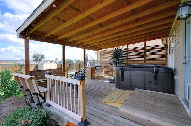 deck featuring an outbuilding, fence, a hot tub, and a shed