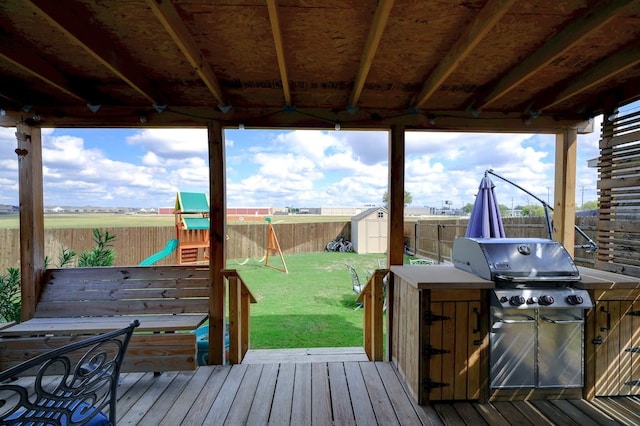 wooden deck featuring a lawn, a fenced backyard, an outdoor structure, a shed, and a playground