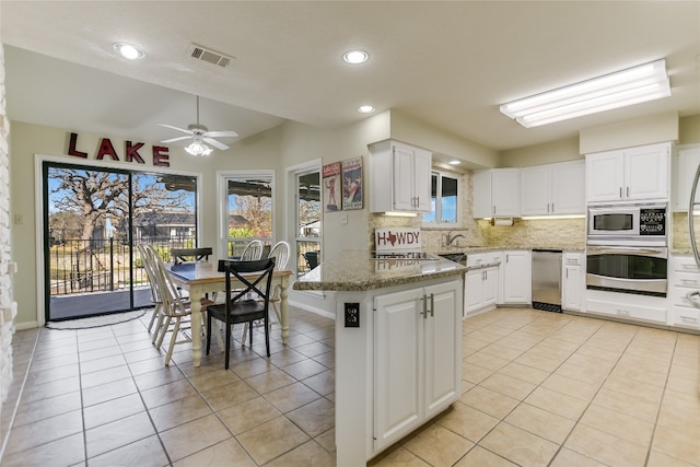 100 Boot Hl, Horseshoe Bay, TX 78657 - kitchen featuring a peninsula, visible vents, stainless steel oven, white cabinetry, and dark stone countertops