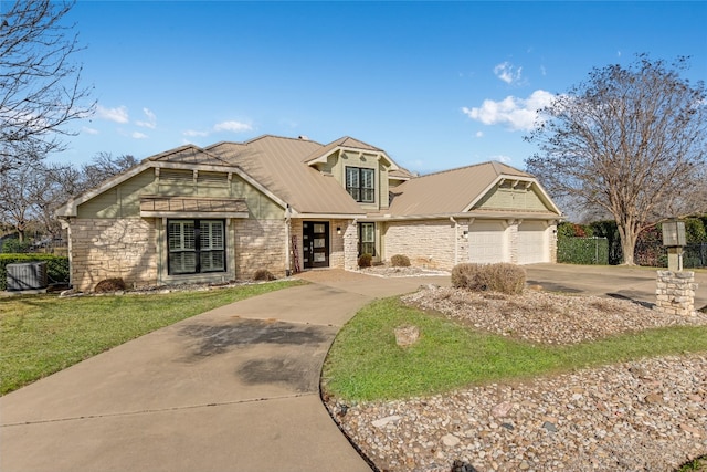 view of front of home featuring concrete driveway, an attached garage, metal roof, stone siding, and a front lawn