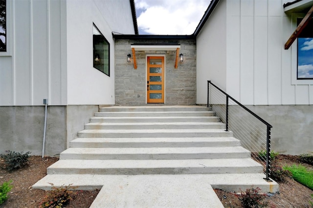 view of exterior entry featuring stone siding and board and batten siding