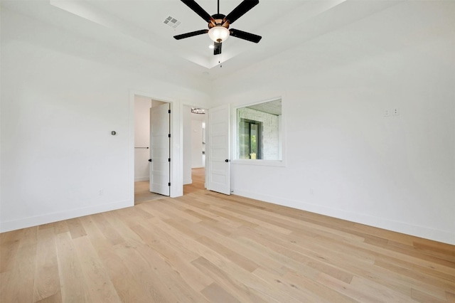 unfurnished bedroom featuring light wood-type flooring, a raised ceiling, visible vents, and baseboards