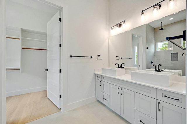 bathroom with baseboards, walk in shower, and a sink