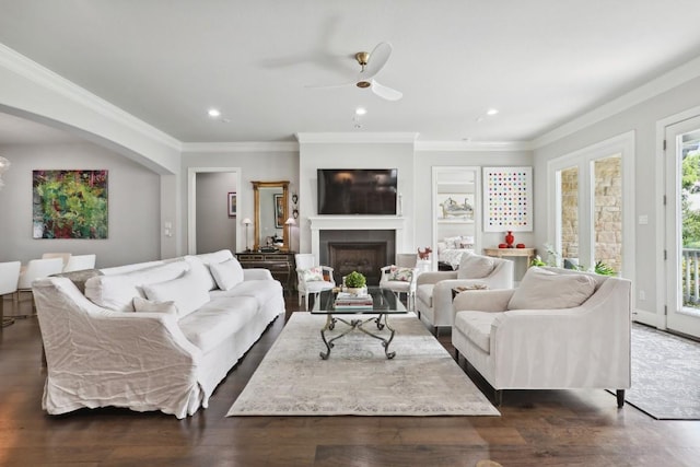 living room featuring dark wood-type flooring, a fireplace, and crown molding