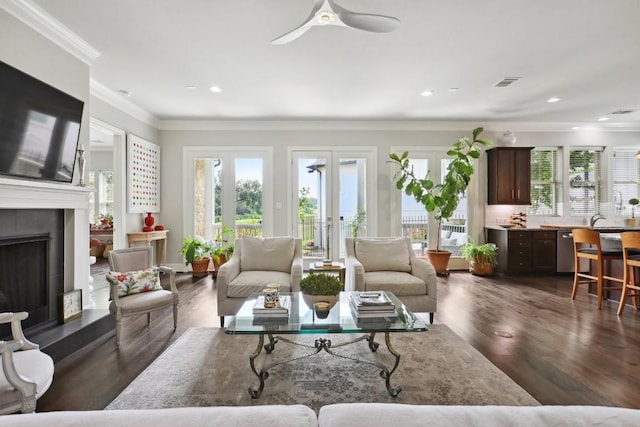 living room with plenty of natural light, visible vents, a fireplace with raised hearth, and dark wood-type flooring