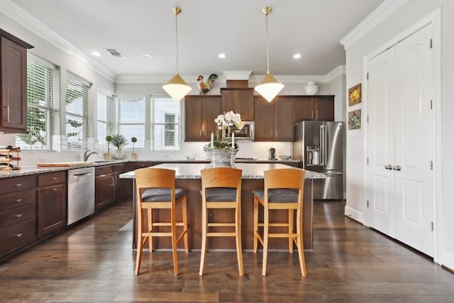 kitchen with stainless steel appliances, visible vents, a kitchen island, and light stone counters