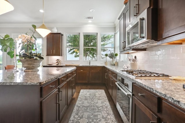 kitchen with visible vents, ornamental molding, decorative light fixtures, light stone countertops, and stainless steel appliances