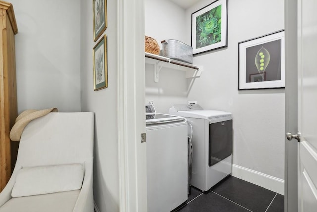 clothes washing area featuring baseboards, laundry area, dark tile patterned flooring, and washer and dryer