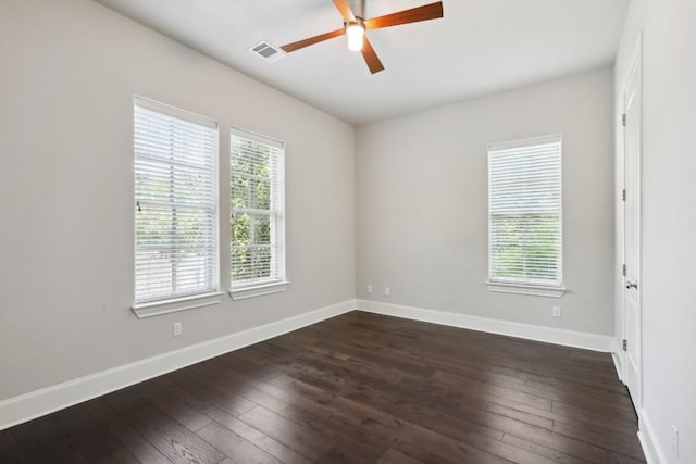 empty room with a ceiling fan, dark wood-style flooring, visible vents, and baseboards