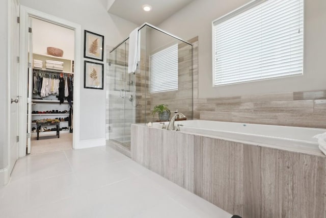 full bathroom featuring a stall shower, a walk in closet, a garden tub, and tile patterned floors