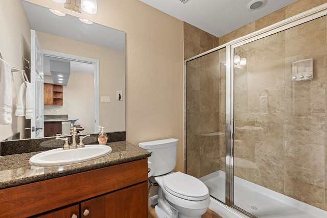 bathroom with a stall shower, vanity, and toilet