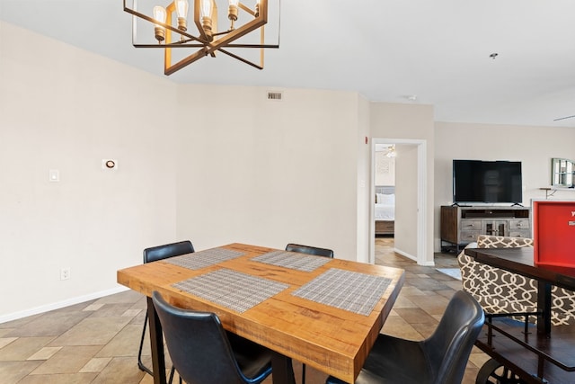 dining area featuring stone finish floor, an inviting chandelier, visible vents, and baseboards