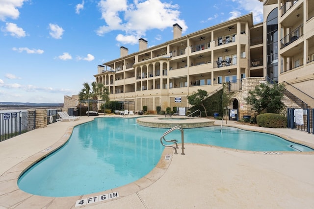 community pool featuring fence, a community hot tub, and a patio