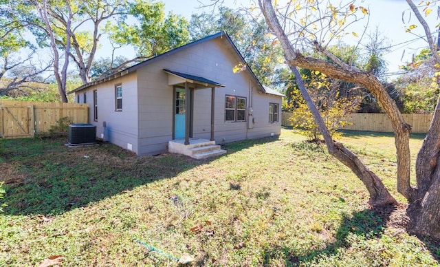 rear view of property featuring cooling unit, a fenced backyard, and a yard