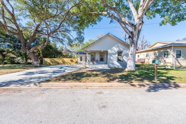 bungalow-style house with covered porch, fence, and concrete driveway